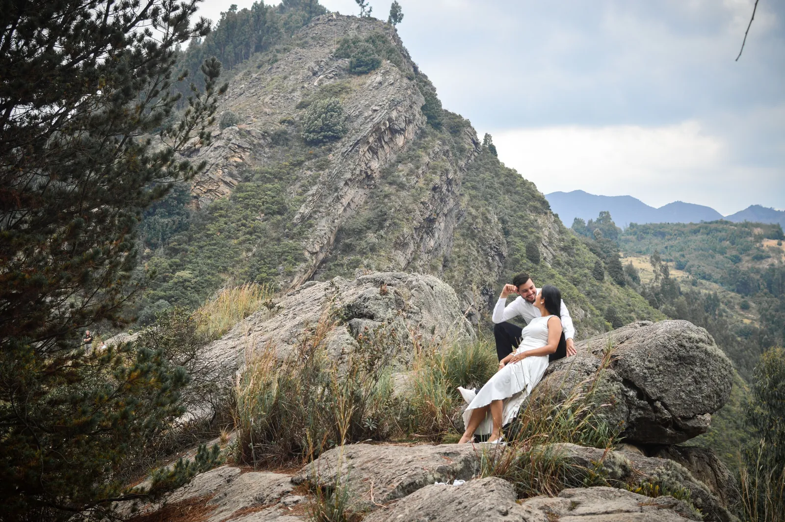 La pareja sentada en la roca con la montaña de fondo